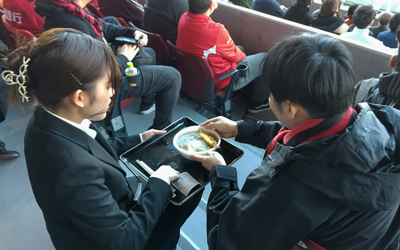 座席に配達された蕎麦を受け取る来場客